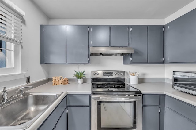 kitchen with stainless steel range with electric stovetop, gray cabinets, a sink, and exhaust hood