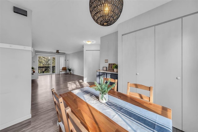 dining space with ceiling fan with notable chandelier, wood finished floors, and baseboards