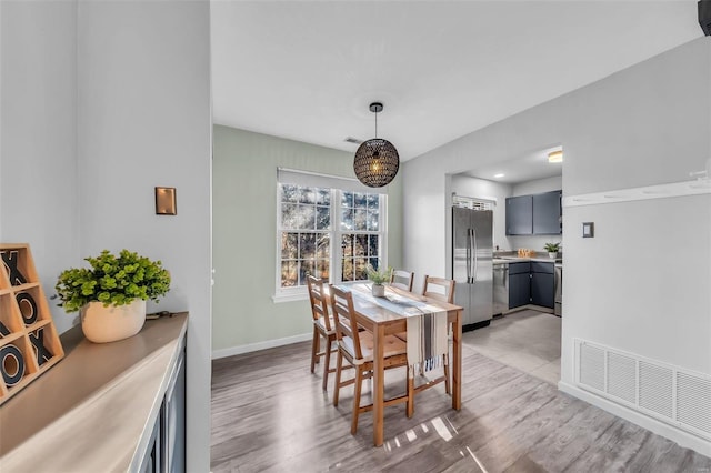 dining room with baseboards, visible vents, and light wood finished floors