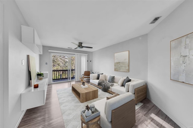 living room featuring baseboards, wood finished floors, visible vents, and a ceiling fan