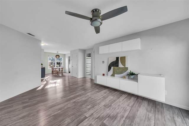 unfurnished living room featuring a ceiling fan, baseboards, visible vents, and wood finished floors