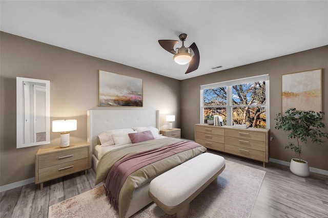 bedroom with baseboards, ceiling fan, visible vents, and light wood finished floors