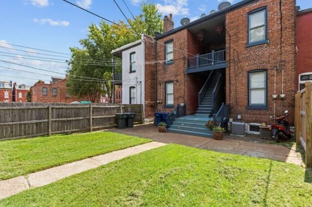 back of house with a yard and central AC unit