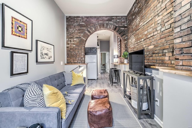 living room with light hardwood / wood-style floors and brick wall