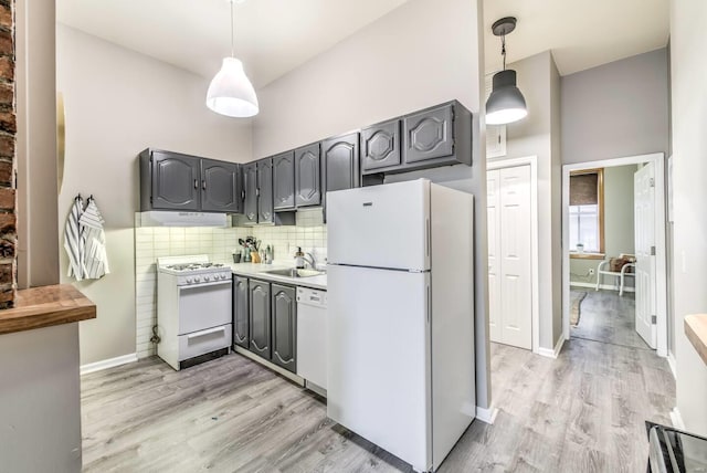 kitchen featuring pendant lighting, white appliances, sink, light hardwood / wood-style flooring, and gray cabinets