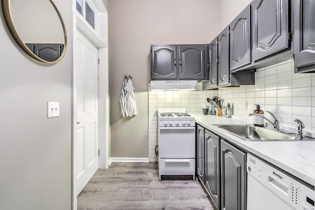 kitchen with decorative backsplash, hardwood / wood-style floors, white appliances, and sink