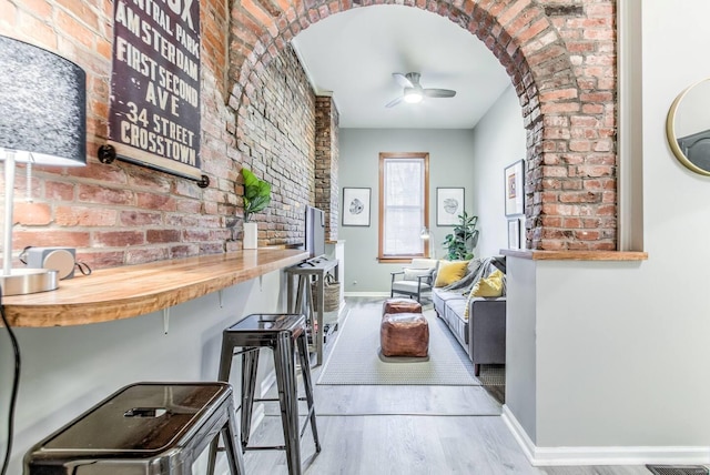 hall with light wood-type flooring and brick wall