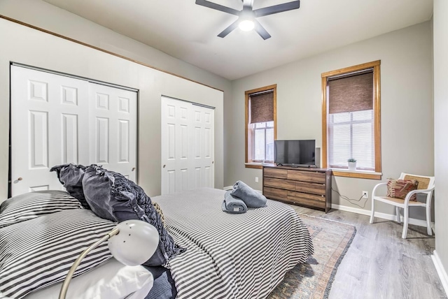 bedroom featuring ceiling fan, light wood-type flooring, and multiple closets