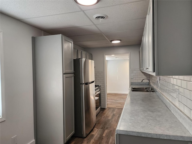 kitchen with a drop ceiling, dark wood-type flooring, sink, gray cabinets, and appliances with stainless steel finishes