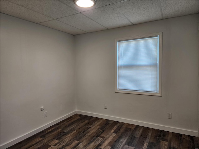 spare room with dark hardwood / wood-style flooring and a drop ceiling