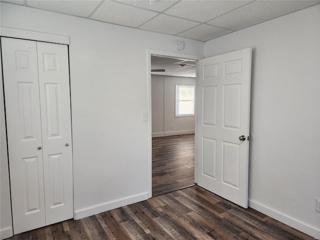 unfurnished bedroom featuring dark hardwood / wood-style flooring, a closet, and a paneled ceiling