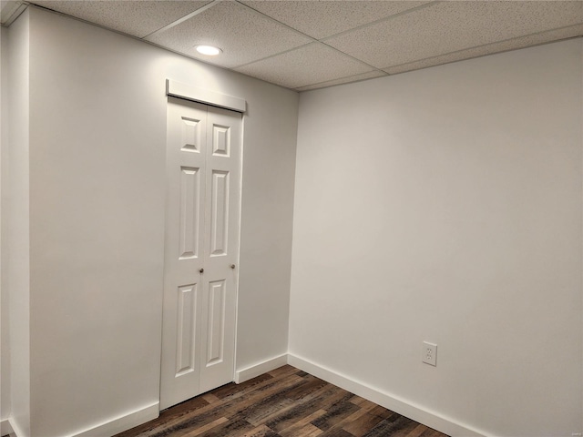 unfurnished room with a paneled ceiling and dark hardwood / wood-style floors