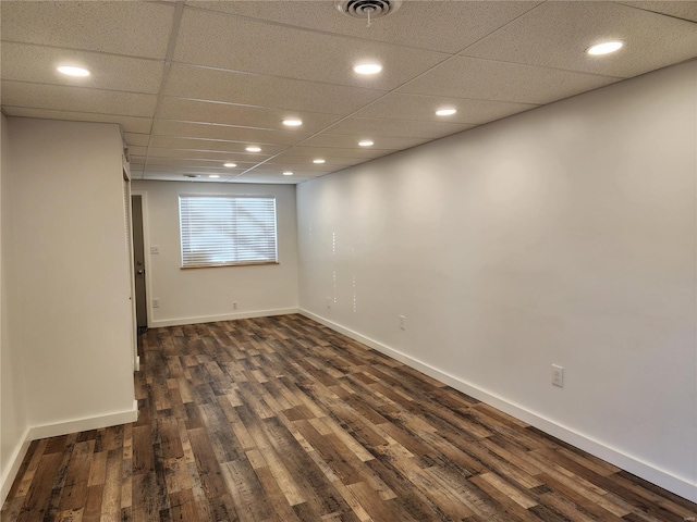 spare room with a paneled ceiling and dark hardwood / wood-style flooring