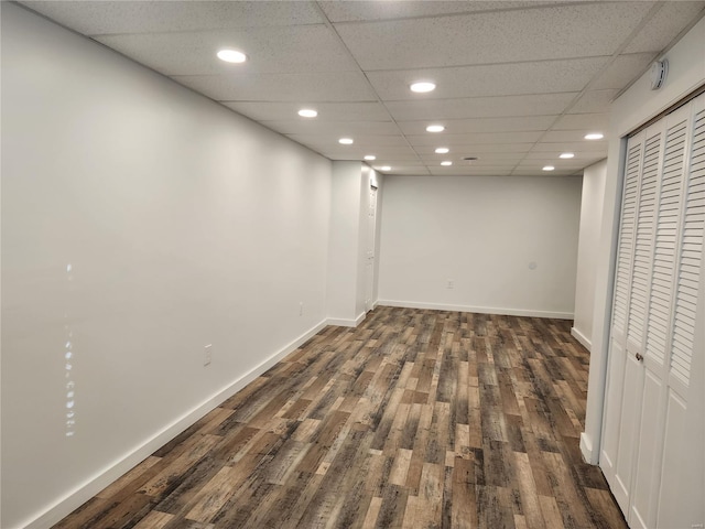 basement with a drop ceiling and dark wood-type flooring