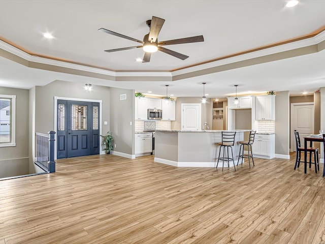 interior space with a tray ceiling, light hardwood / wood-style floors, and ornamental molding