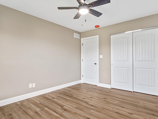 unfurnished bedroom featuring a closet, light hardwood / wood-style floors, and ceiling fan