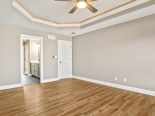 spare room with a raised ceiling, ornamental molding, and hardwood / wood-style flooring