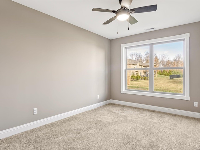 carpeted spare room featuring plenty of natural light and ceiling fan