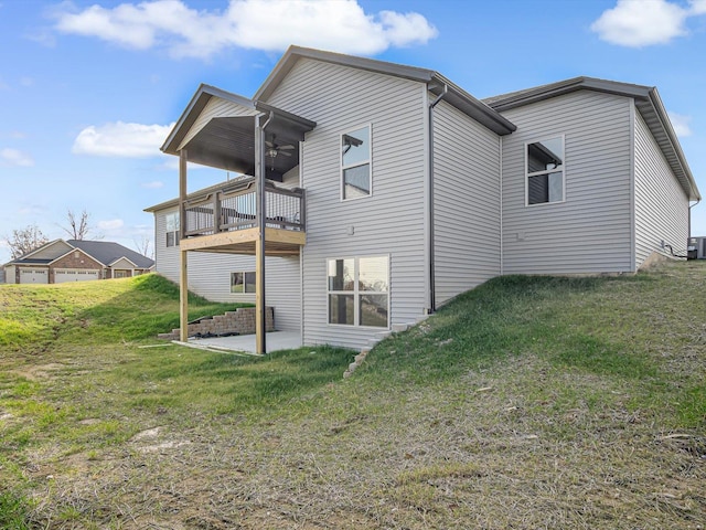 rear view of property featuring a balcony, ceiling fan, central AC unit, a patio area, and a yard