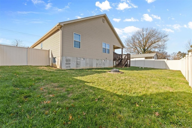 rear view of house featuring a fenced backyard, a yard, and stairway