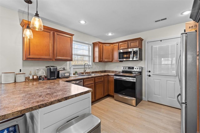 kitchen featuring stainless steel appliances, brown cabinetry, visible vents, and a sink