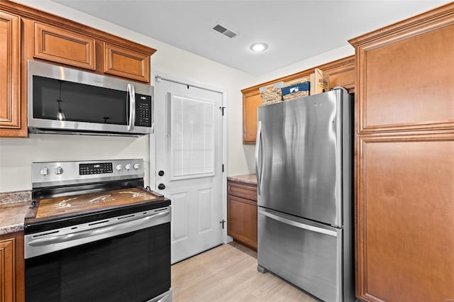 kitchen with recessed lighting, visible vents, appliances with stainless steel finishes, light wood-type flooring, and brown cabinets