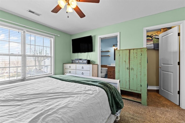 carpeted bedroom with visible vents, ceiling fan, and ensuite bathroom