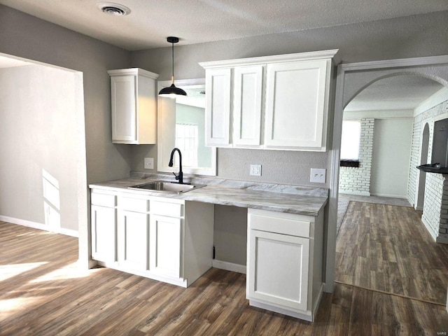 kitchen featuring dark wood-type flooring, sink, decorative light fixtures, a textured ceiling, and white cabinets