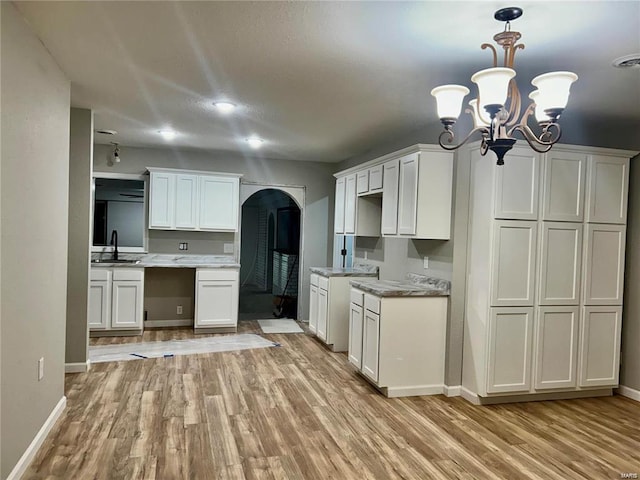 kitchen featuring sink, light hardwood / wood-style floors, a chandelier, and white cabinets