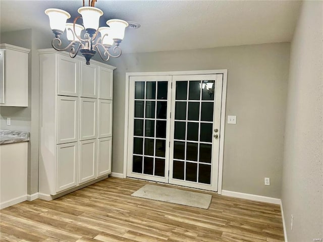 unfurnished dining area featuring a chandelier and light wood-type flooring