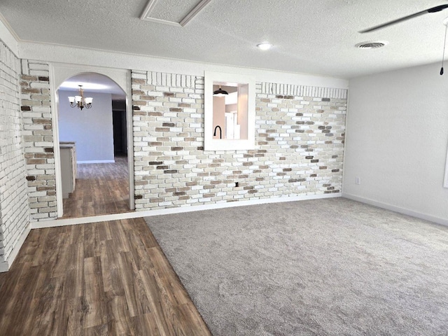 unfurnished room with brick wall, a textured ceiling, and dark hardwood / wood-style flooring