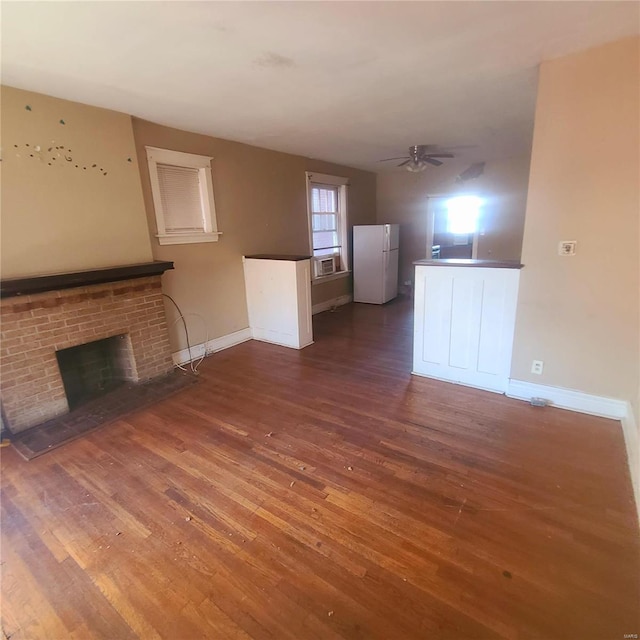 unfurnished living room featuring a brick fireplace, dark hardwood / wood-style floors, ceiling fan, and cooling unit