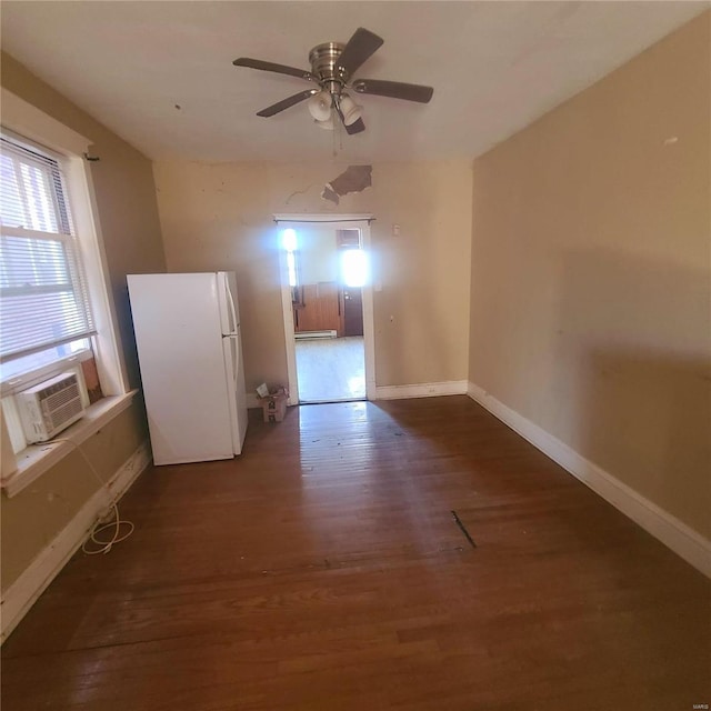 spare room with dark hardwood / wood-style floors, a baseboard radiator, cooling unit, and ceiling fan