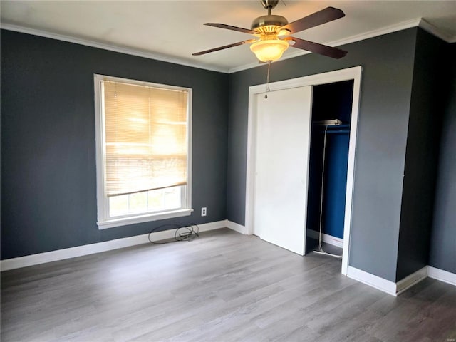 unfurnished bedroom with a closet, hardwood / wood-style flooring, ceiling fan, and crown molding