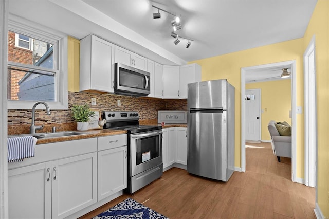 kitchen featuring sink, white cabinets, light wood-type flooring, and appliances with stainless steel finishes