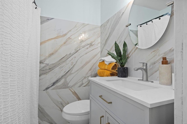 bathroom with vanity, tile walls, and toilet