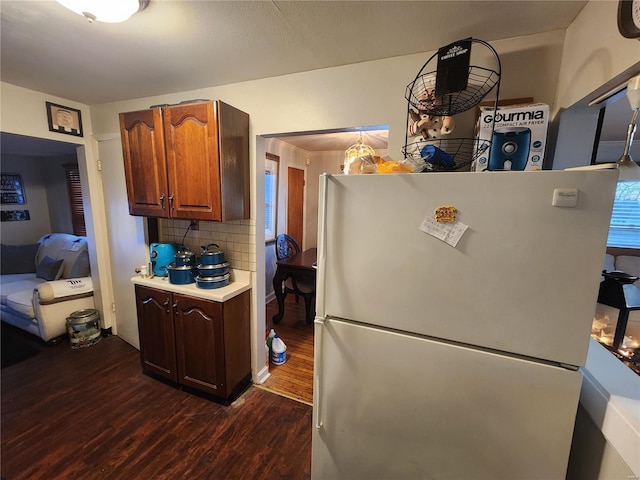 kitchen with decorative backsplash, light countertops, dark wood finished floors, and freestanding refrigerator