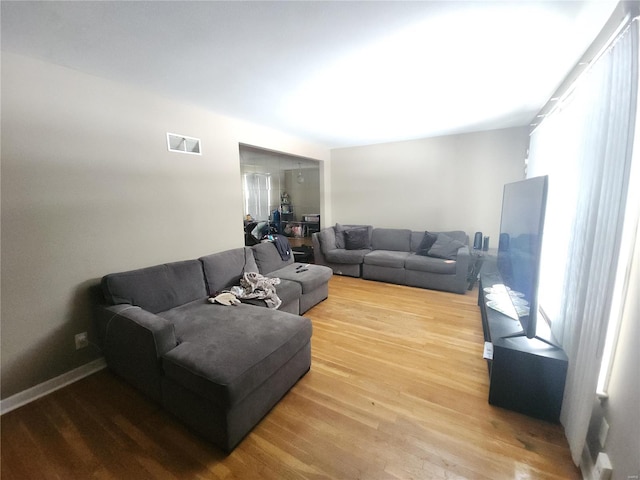 living room with visible vents, baseboards, and wood finished floors