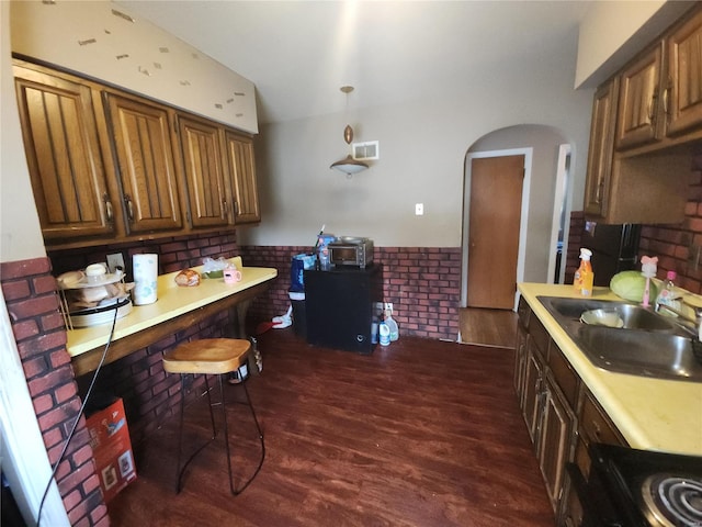 kitchen with a wainscoted wall, dark wood-style flooring, a sink, visible vents, and light countertops