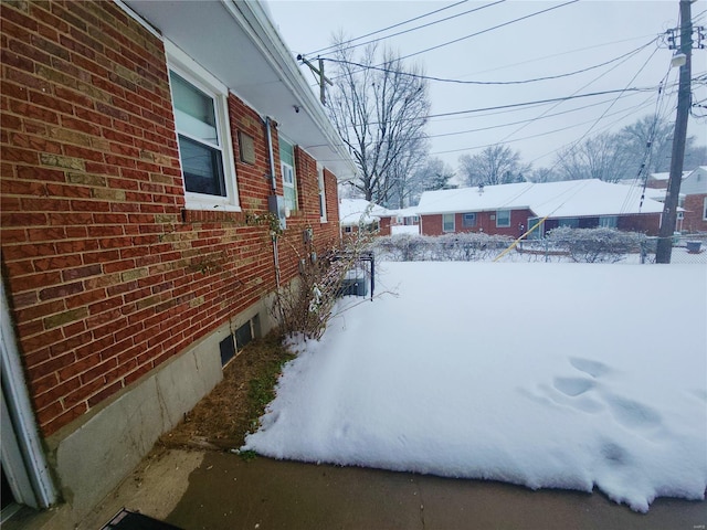 view of snow covered exterior featuring brick siding