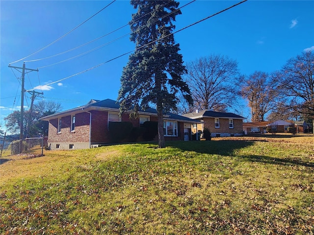 exterior space with brick siding, a lawn, and fence