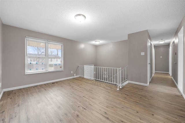 spare room with light hardwood / wood-style flooring and a textured ceiling