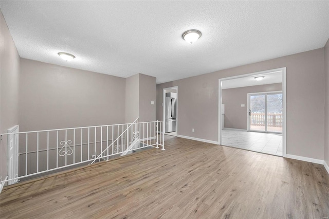 empty room featuring a textured ceiling and light hardwood / wood-style floors