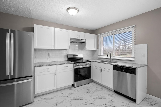 kitchen featuring backsplash, sink, light stone countertops, white cabinetry, and stainless steel appliances