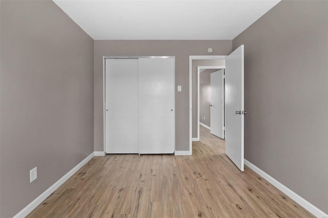 unfurnished bedroom featuring light hardwood / wood-style floors, a textured ceiling, and a closet