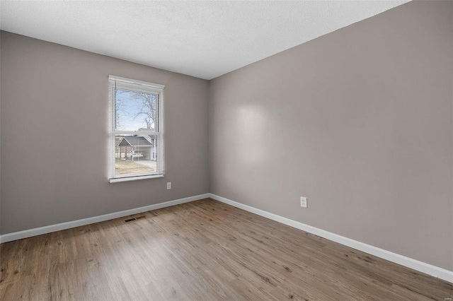 empty room featuring light wood-type flooring and a textured ceiling