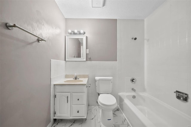 full bathroom with vanity, a textured ceiling, toilet, and tiled shower / bath