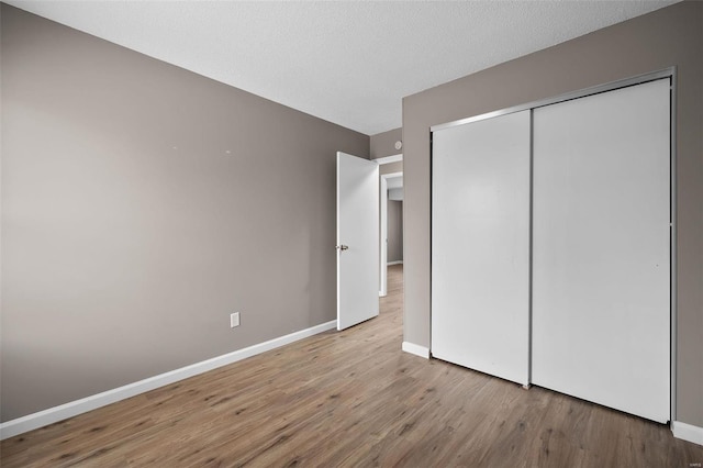 unfurnished bedroom featuring a closet, light hardwood / wood-style flooring, and a textured ceiling