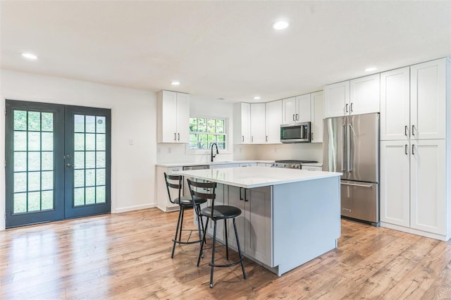 kitchen with sink, a center island, stainless steel appliances, a kitchen breakfast bar, and white cabinets