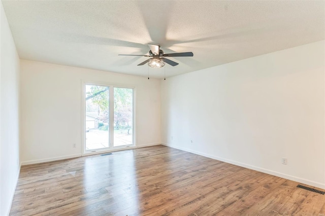 empty room featuring a textured ceiling, light wood-type flooring, and ceiling fan